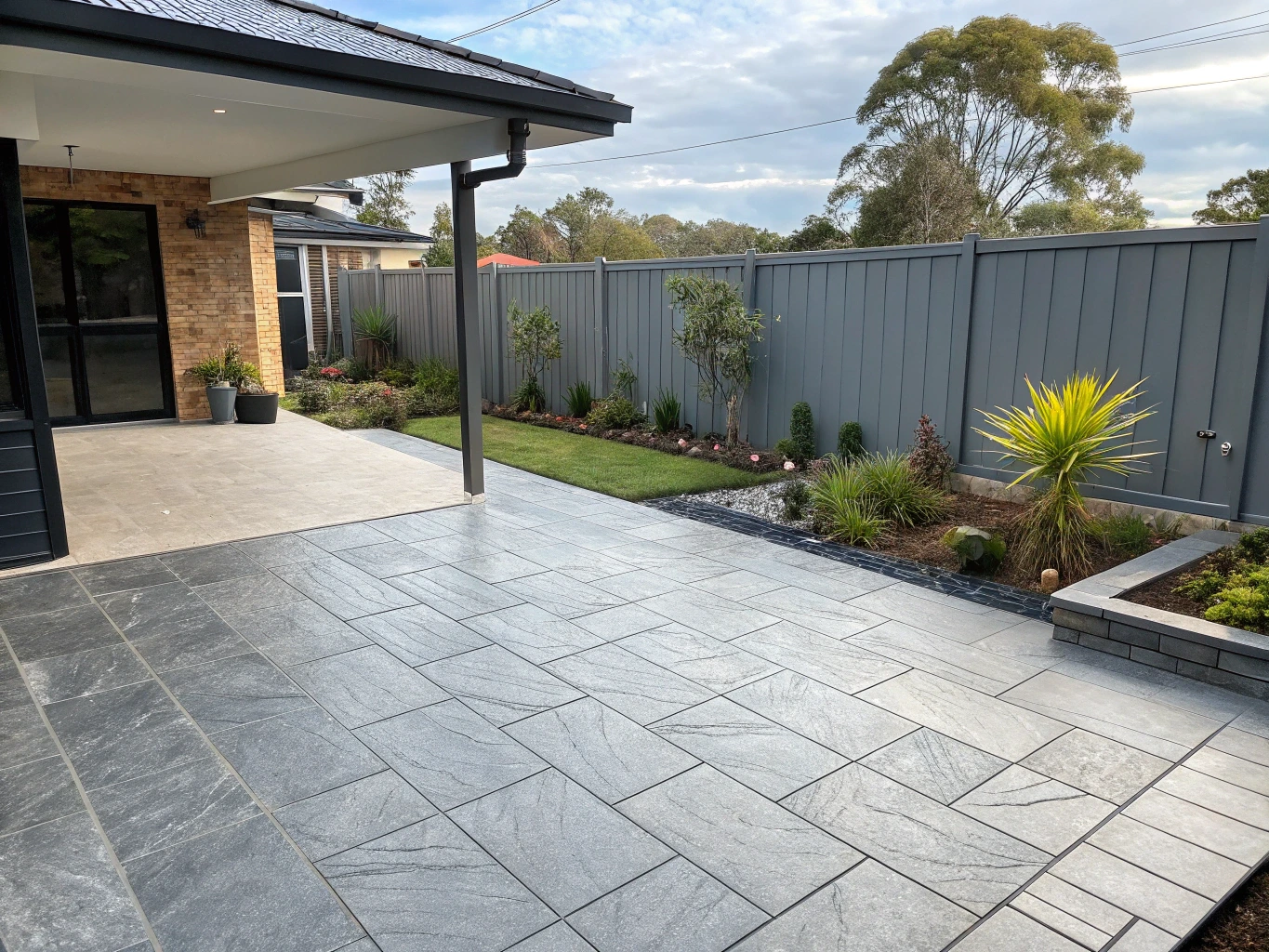 Finished outdoor patio tiling in an Australian backyard with grey textured pavers