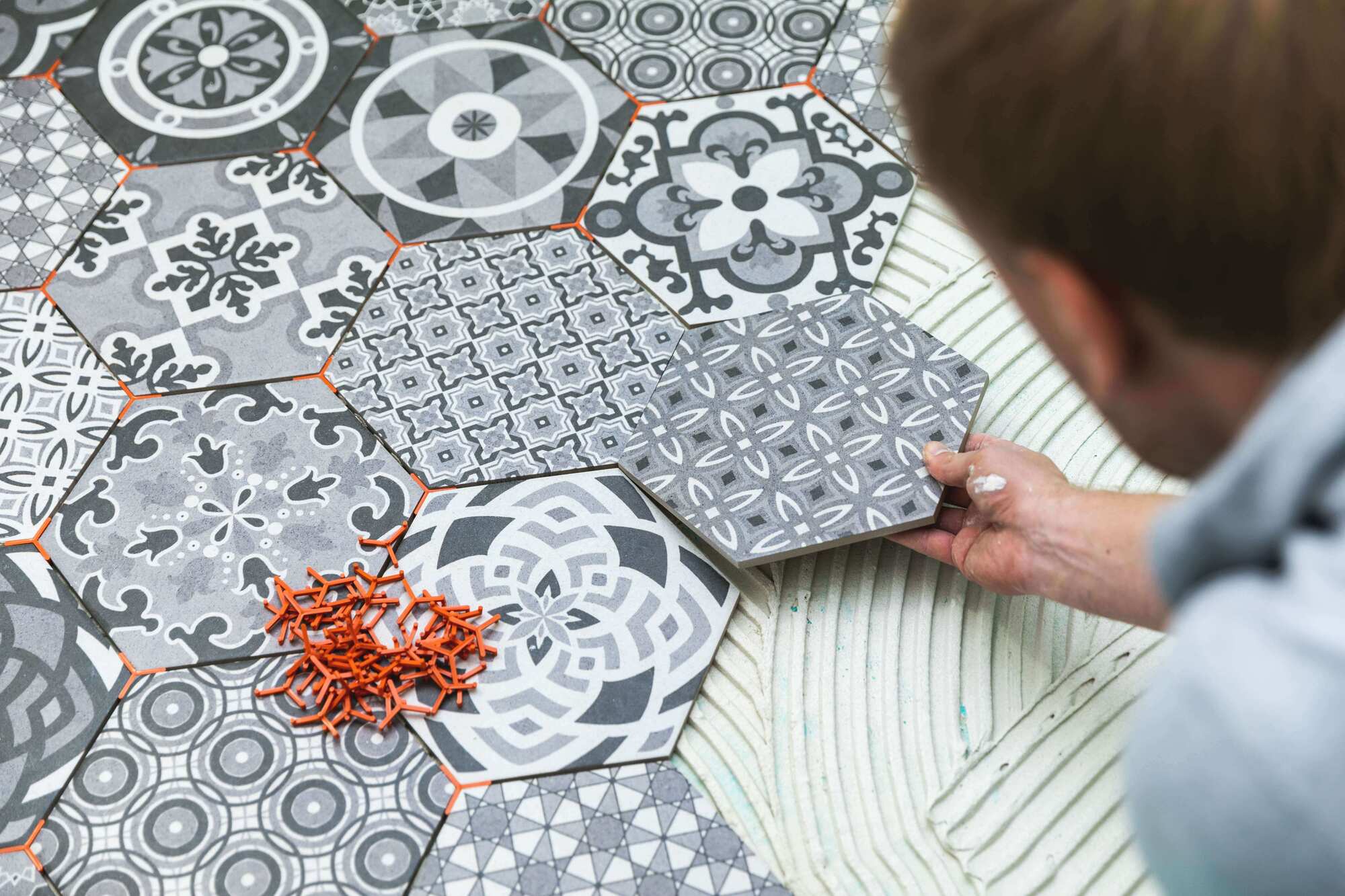 Tiler laying hexagonal patterned tiles with plastic tile spacers