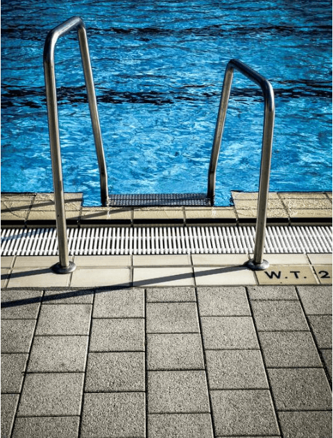 Grey stone-look tiles around the edge of an outdoor swimming pool
