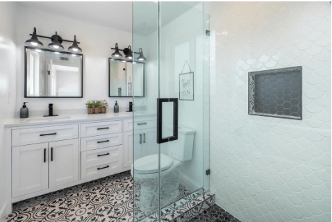 Bathroom with patterned black and white floor tiles and a glass-walled shower