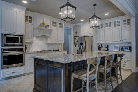Kitchen island with light stone-look floor tiles and pendant lighting