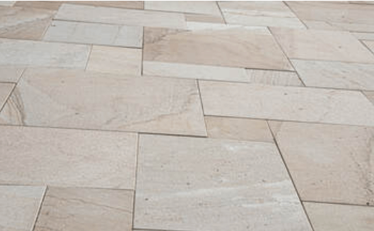 Beige natural stone floor tiles laid in a mixed geometric outdoor pattern