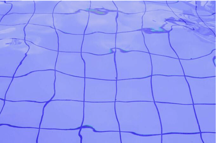 Blue swimming pool tiles seen through clear water