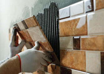 Tiler applying wall tiles with adhesive during a Lake Macquarie job