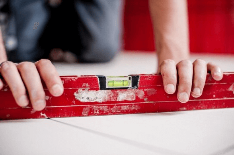 Tiler using a spirit level to check newly laid outdoor floor tiles are even